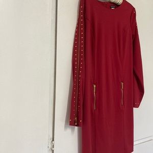 Red dress accessorized with gold studs and gold zippers.